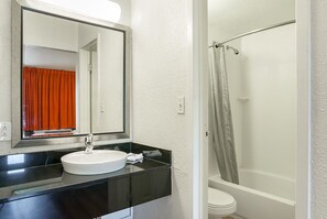 A bathroom with a white sink, a mirror, and a shower area. - Motel 6 Little Rock, AR - West (Little Rock)