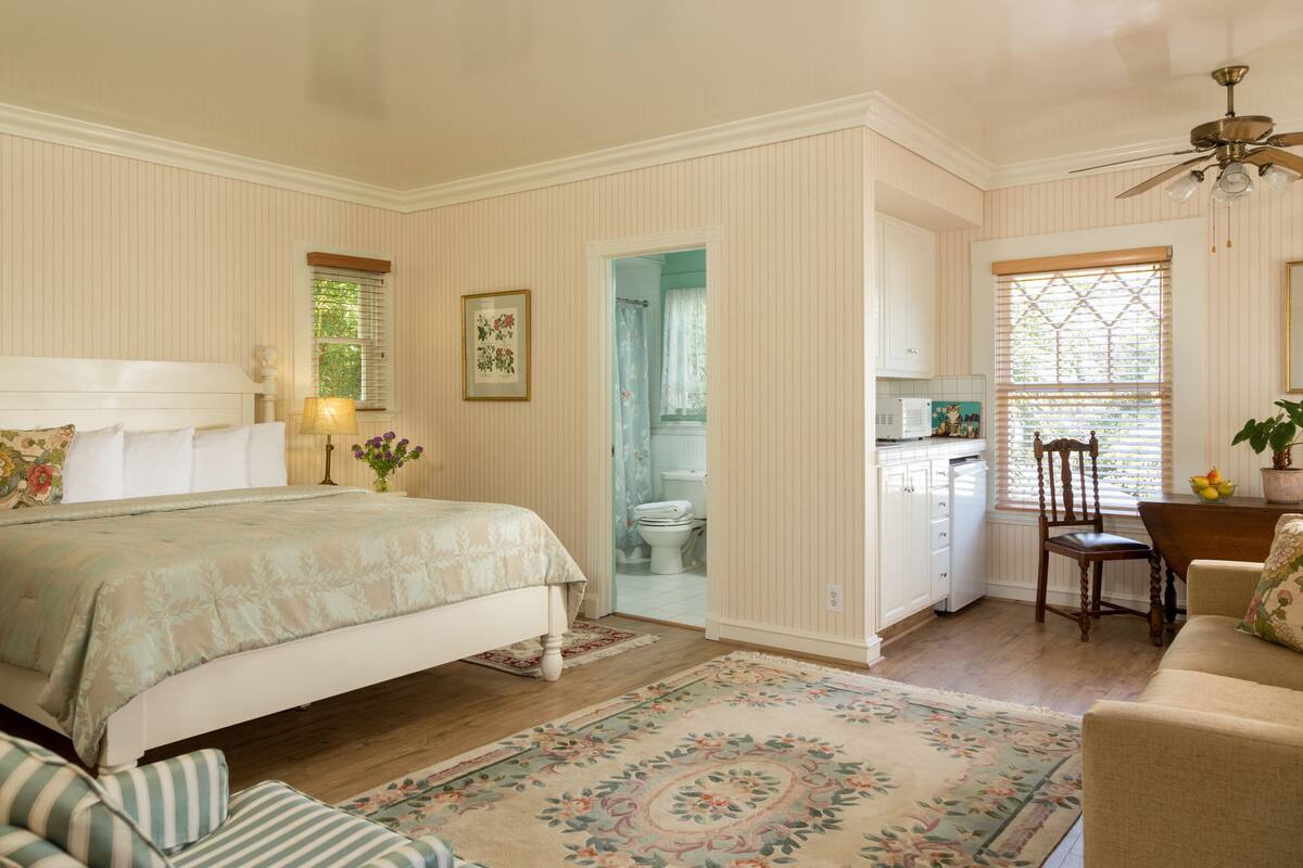 A bedroom with a bed, bedside table, lamp, and a floral rug.