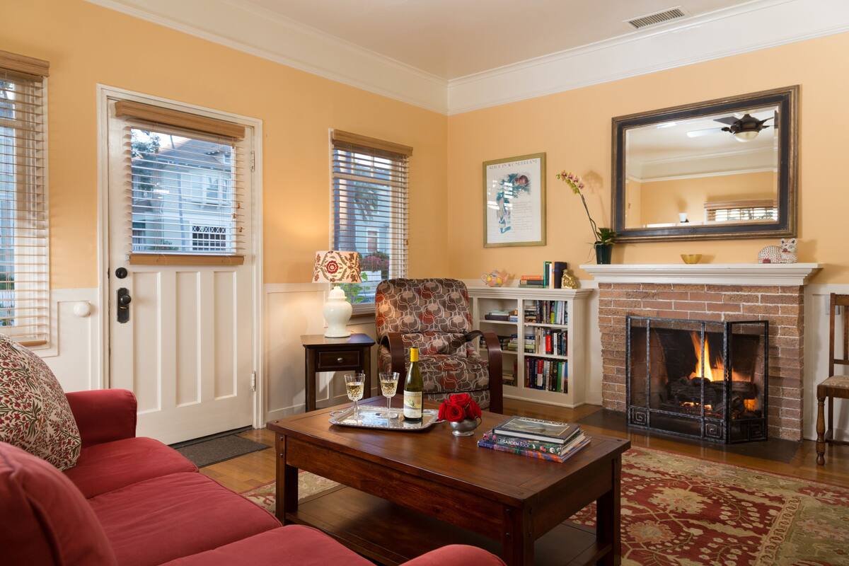 A living room with a fireplace, a red sofa, a wooden coffee table, and a bookshelf.