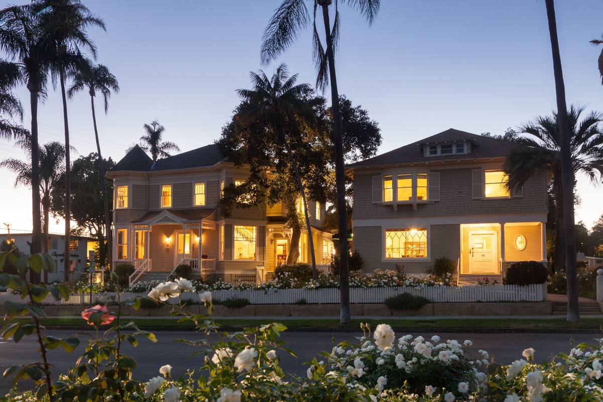 A two-story house with a porch, a garage, and a white picket fence.