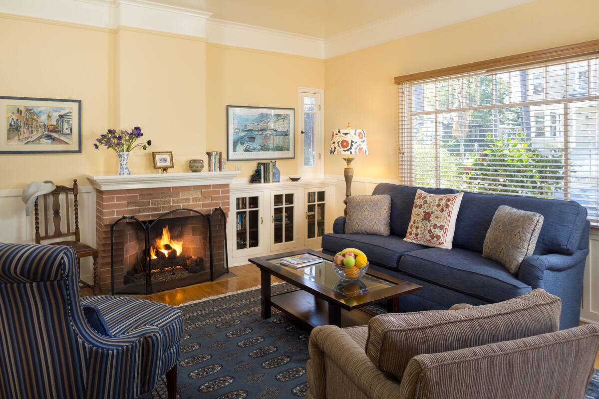 A living room with a fireplace, a sofa, a coffee table, and a patterned rug.