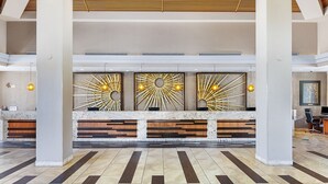 Een receptiezone met een modern design, met een marmeren receptiebalie, houten details en een zonachtige wanddecoratie.