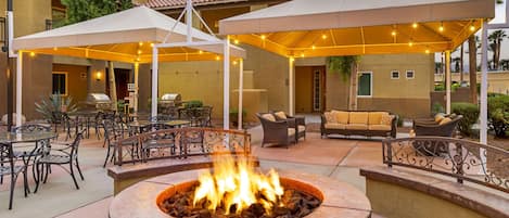 An outdoor patio area with a fire pit, seating, and umbrellas.