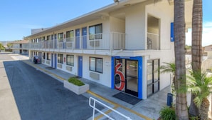 A motel with a blue entrance, multiple balconies, and a parking lot. - Motel 6 San Ysidro, CA - San Diego - Border (San Ysidro)