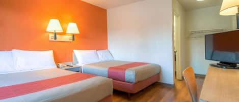 A hotel room with two beds, a desk with a chair, a television, and two wall-mounted lamps.