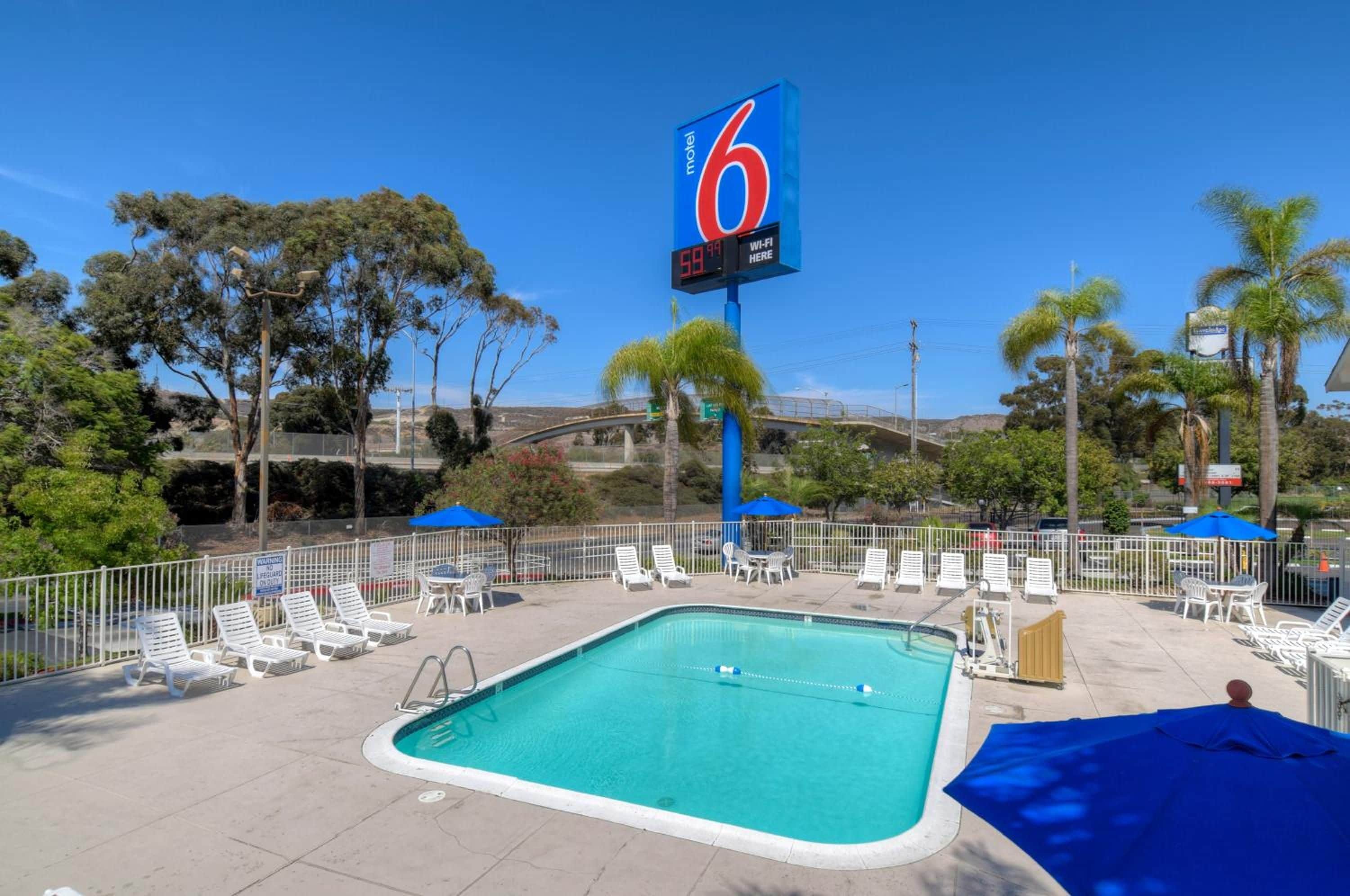 Un motel doté d’un espace piscine, comprenant des chaises longues et des parasols.