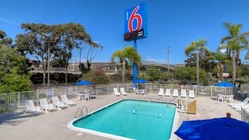 Un motel doté d’un espace piscine, comprenant des chaises longues et des parasols.