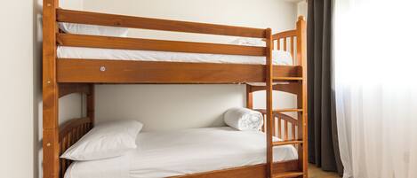A bunk bed with a wooden frame, white bedding, and a ladder.
