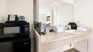A modern bathroom with a built-in microwave, a coffee maker, a sink, and a mirror. - Vagabond Inn Los Angeles at USC (Los Angeles)