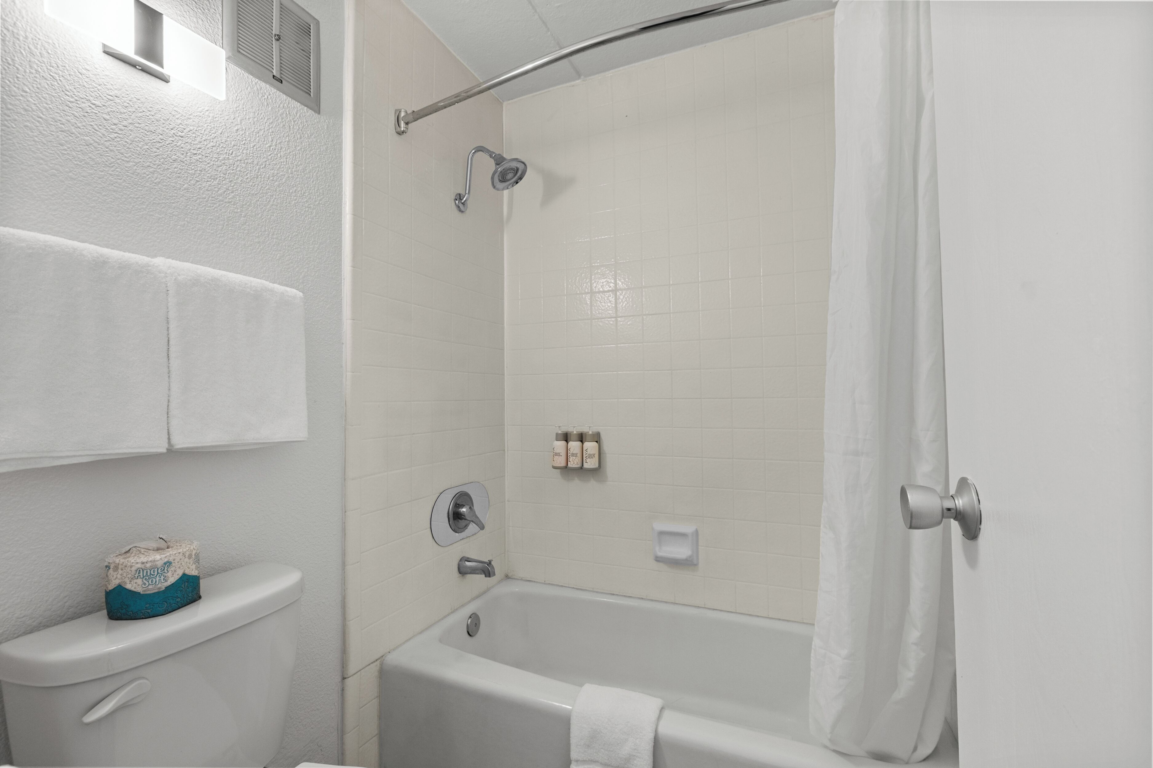 Un baño con inodoro, bañera, ducha y un perchero para toallas.