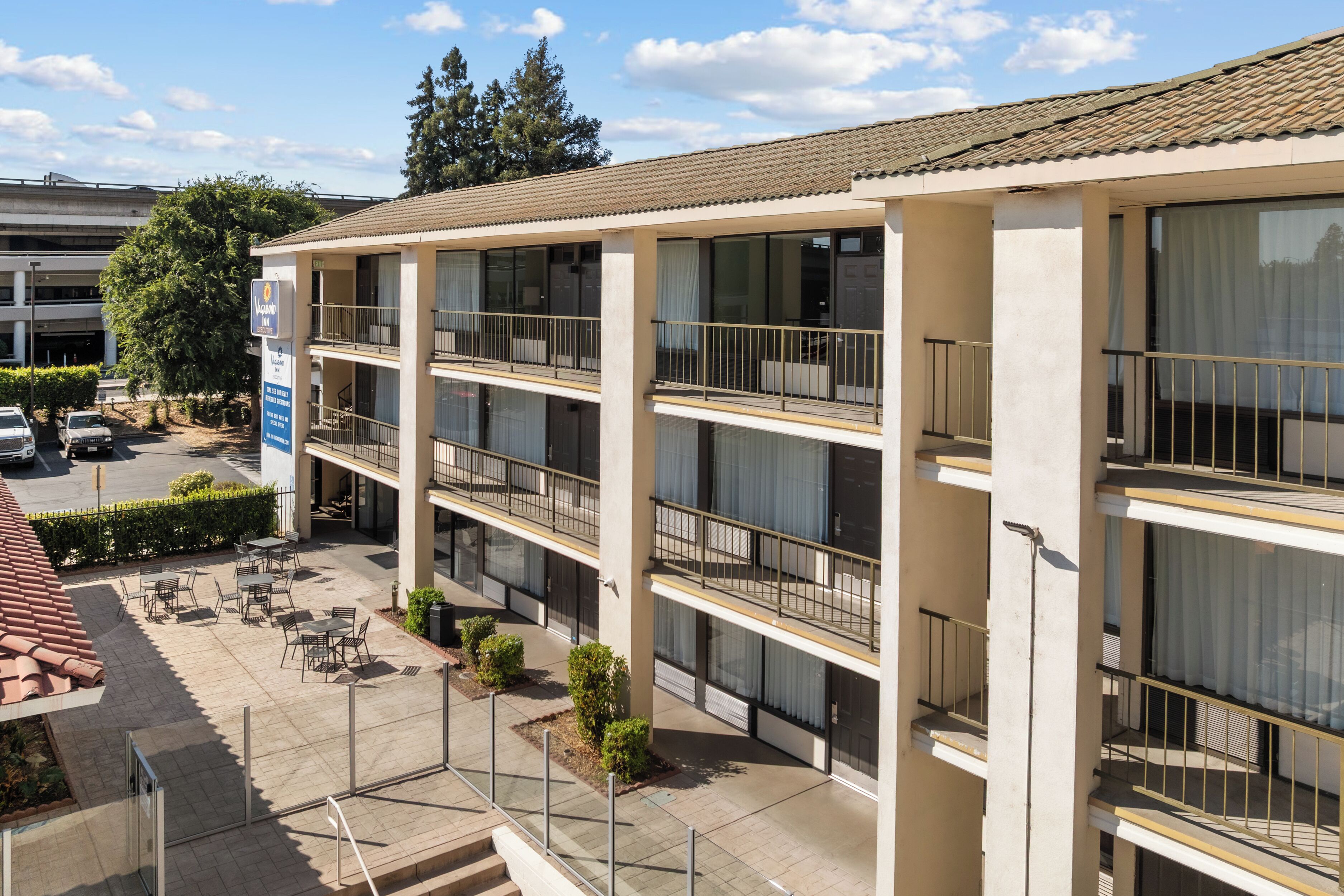 A multi-story hotel with outdoor seating and a parking area.