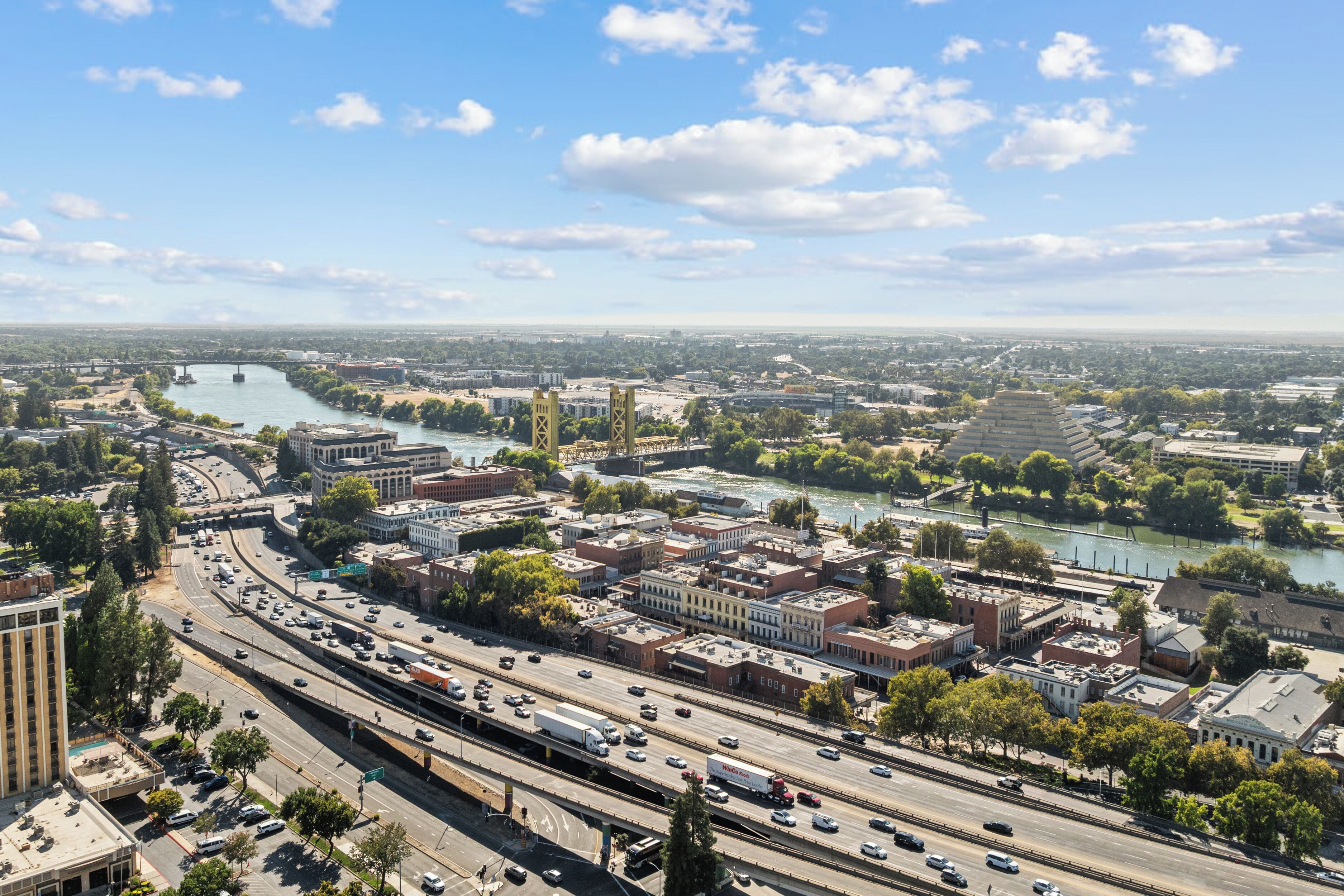 A cityscape with a river, multiple bridges, and a highway with moving vehicles.