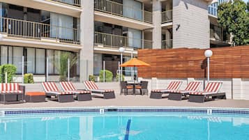A swimming pool with lounge chairs and a wooden deck.