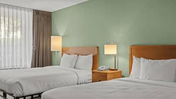 Een hotelkamer met twee bedden, een houten hoofdeinde, een nachtkastje met een lamp en een telefoon.