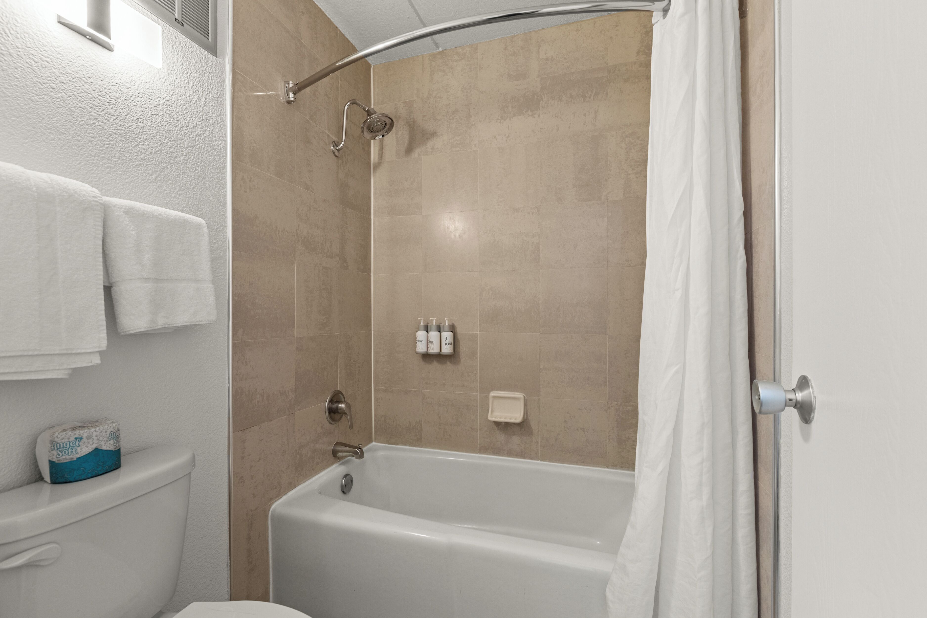A bathroom with a bathtub, toilet, and shower curtain.