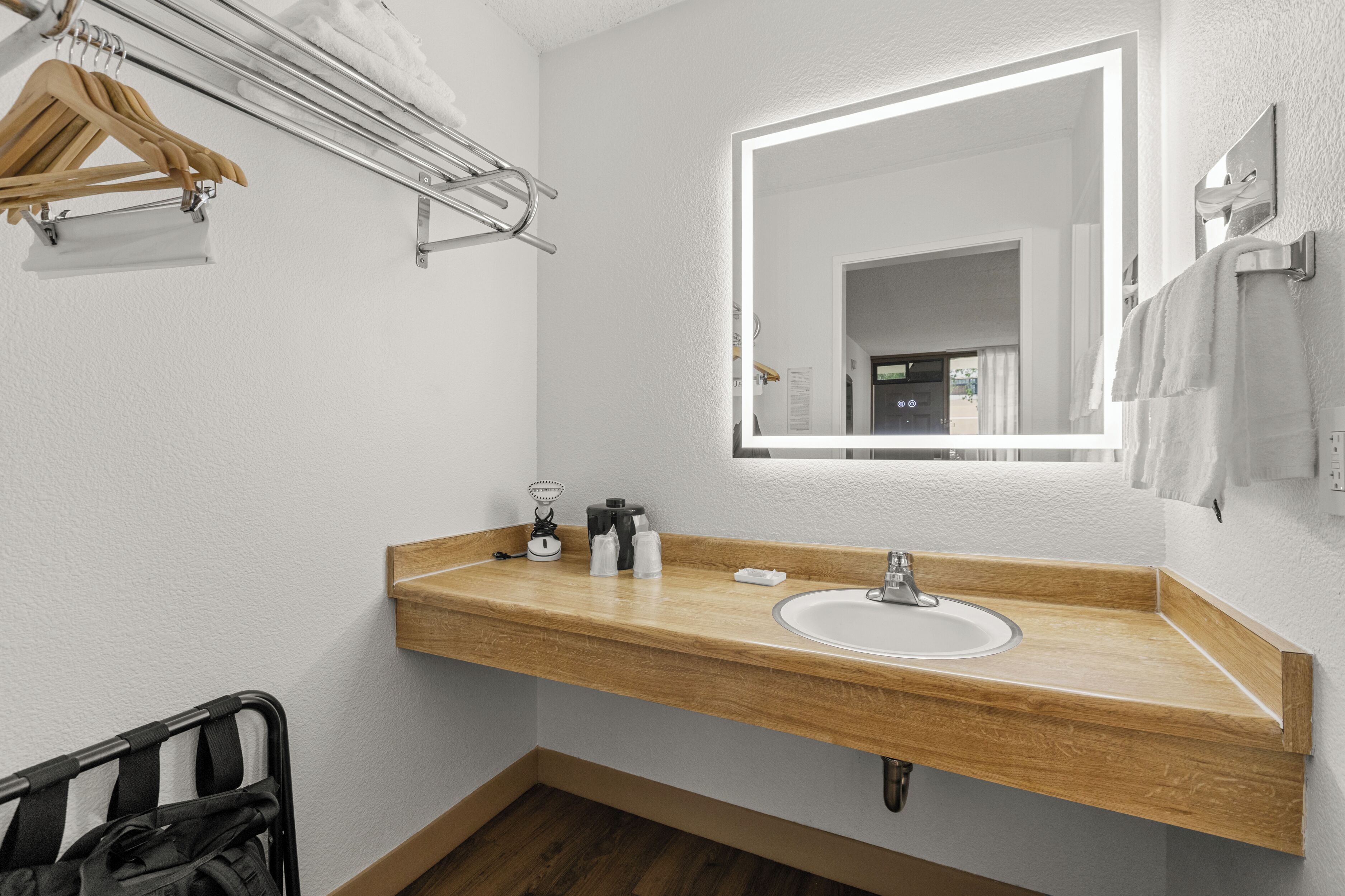 A bathroom with a wooden vanity, a sink, a mirror, and a towel rack.