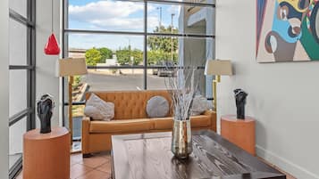 A modern living room with a large window, a brown sofa, a coffee table, and two lamps.