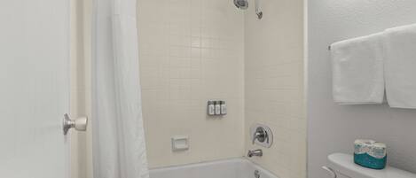 A bathroom with a bathtub, toilet, and shower curtain.