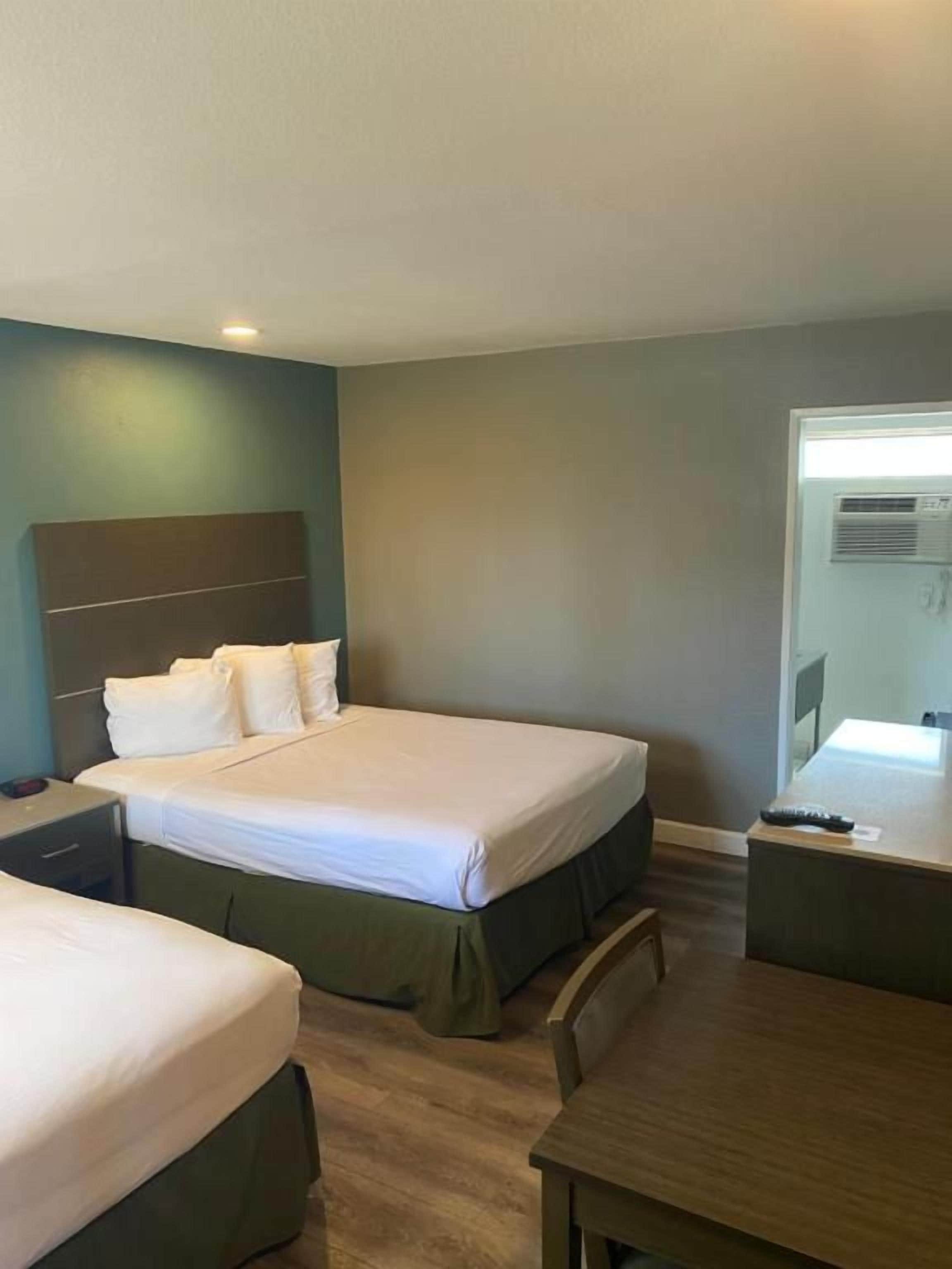 Une chambre d’hôtel avec deux lits, un bureau et une chaise.