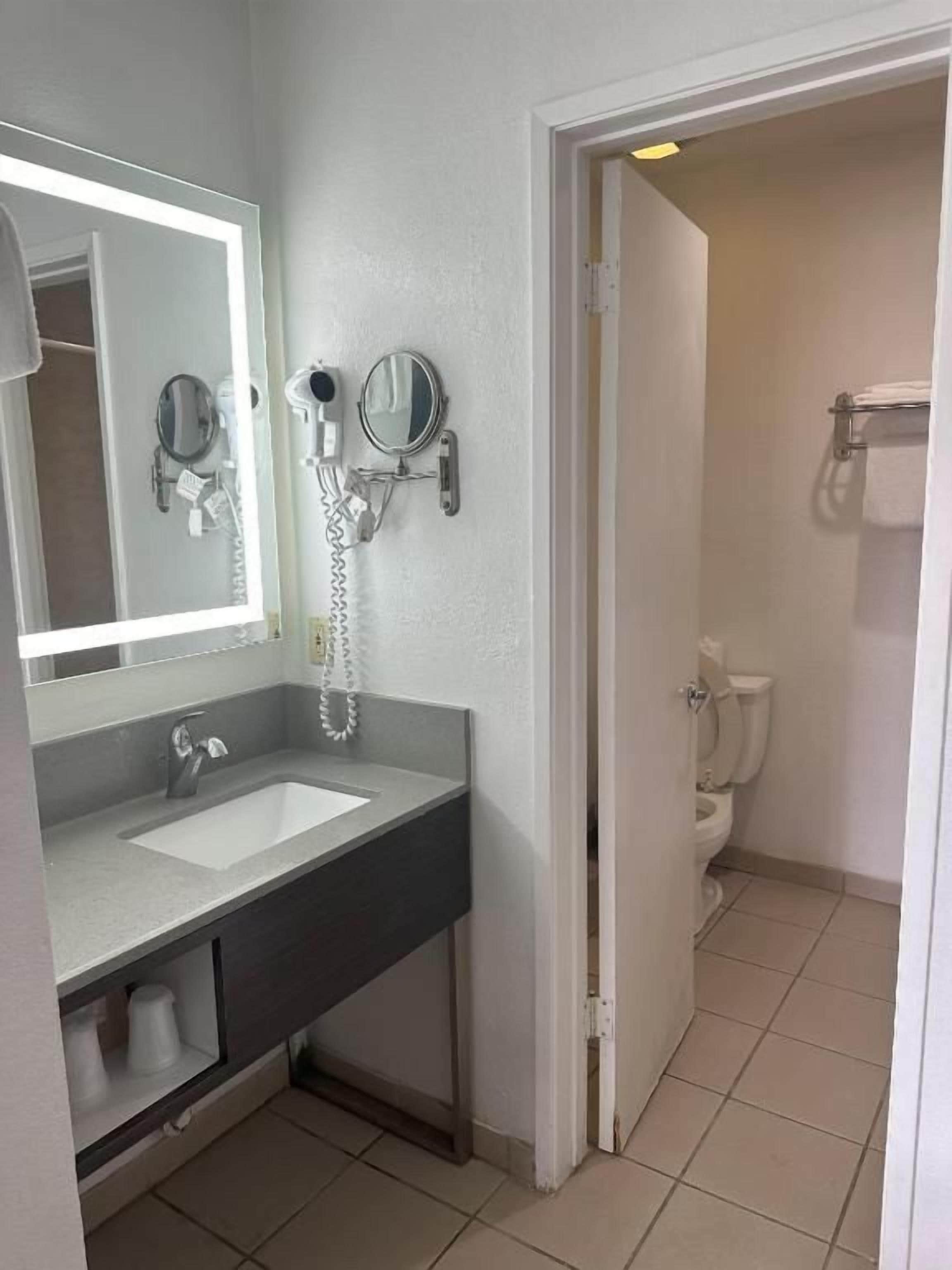 Un bagno con lavandino, specchio e due asciugacapelli montati a parete.