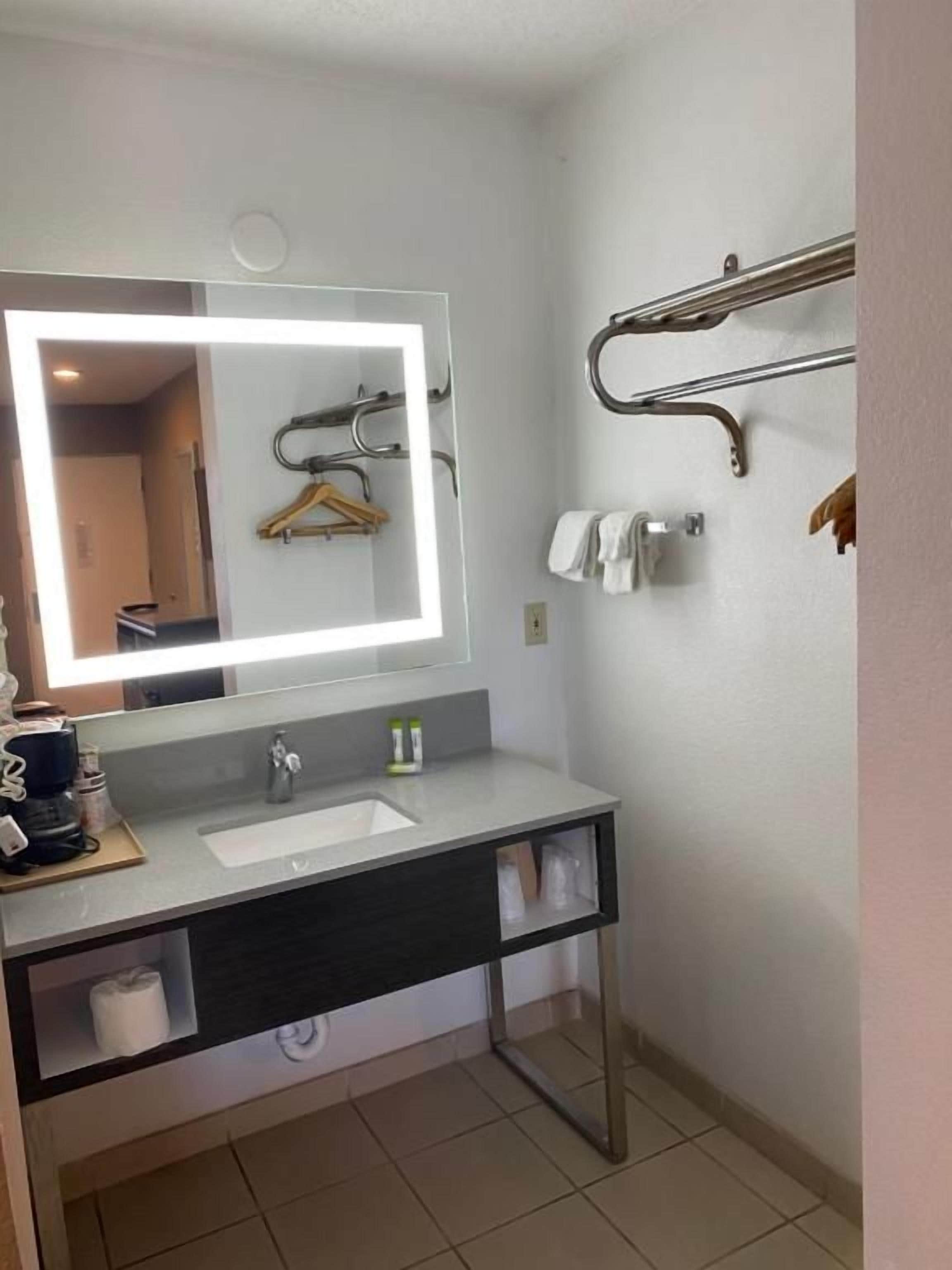 A modern bathroom with a large mirror, a sink, and a towel rack.