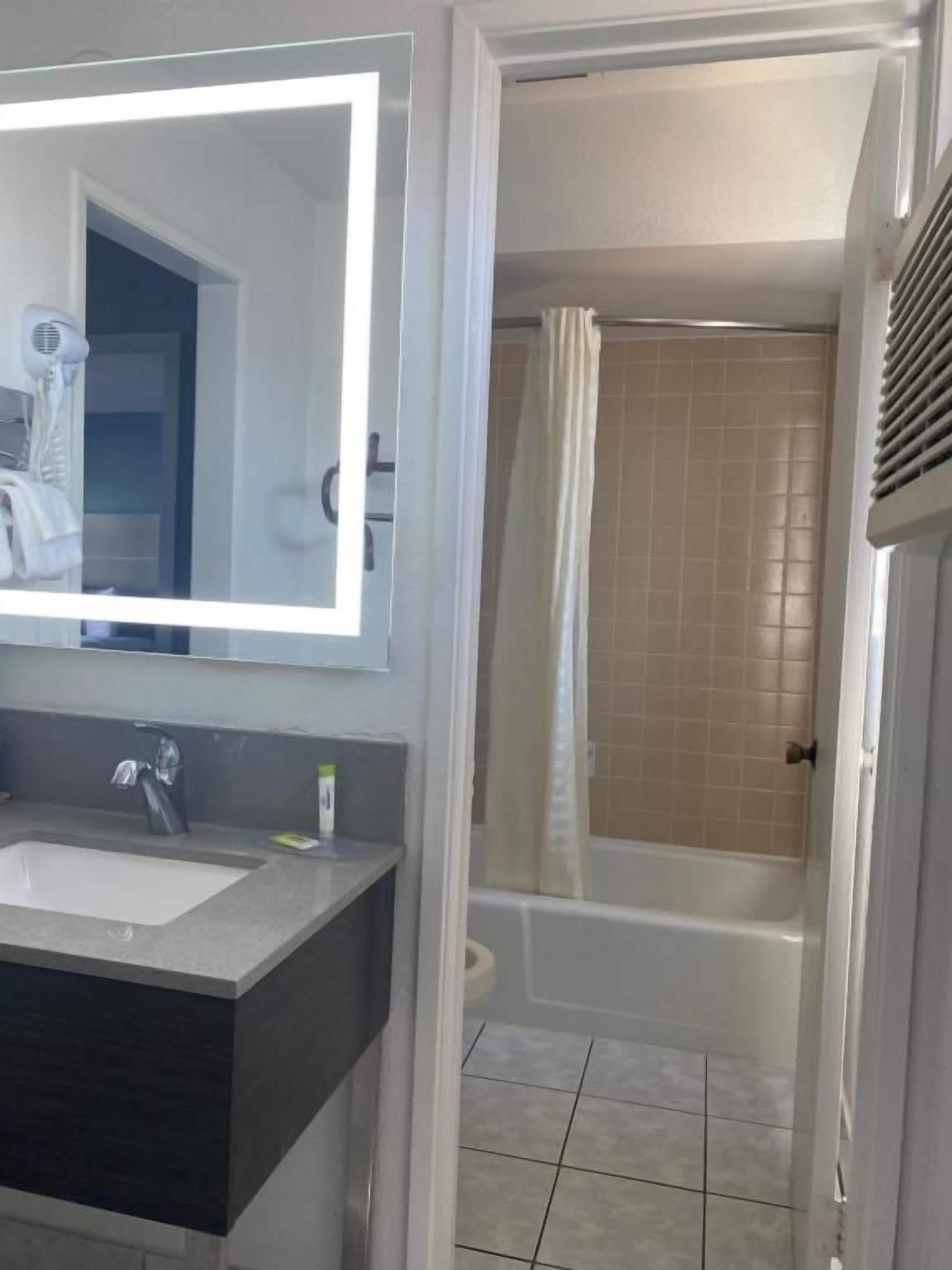 Een badkamer met een wastafel, spiegel en douche.