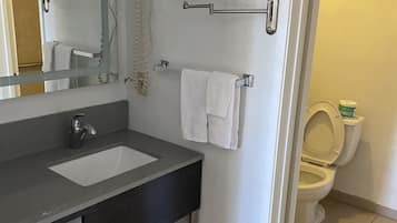 A bathroom with a sink, mirror, towel rack, and toilet.