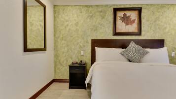 Quarto de hotel com uma cama, uma mesa de cabeceira, um quadro na parede e um espelho.