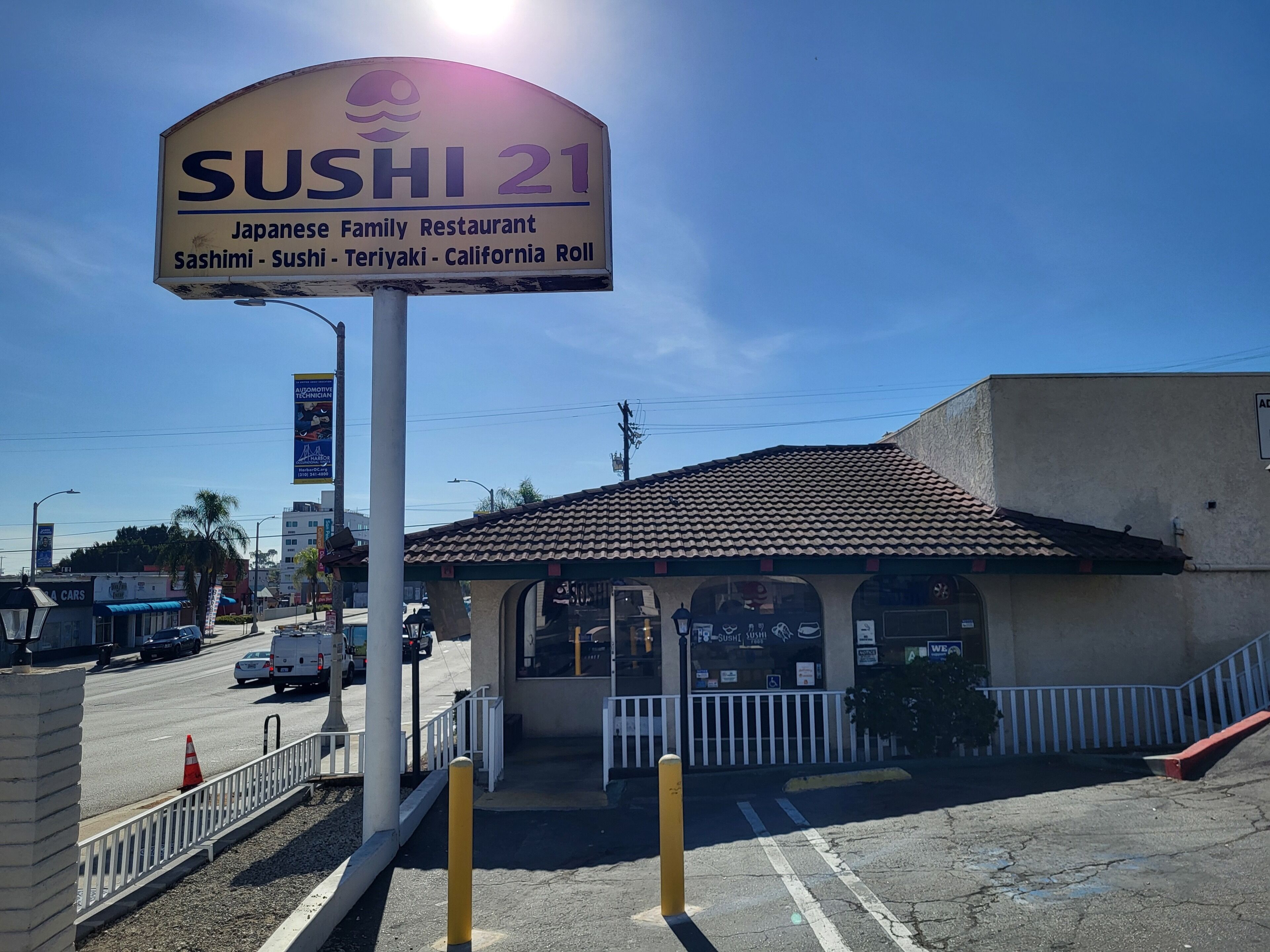 A sign for 'SUSHI 21 Japanese Family Restaurant' with a clear view of the building's entrance and surrounding street.