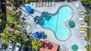 An aerial view of a swimming pool area with lounge chairs, umbrellas, and a parking lot. - Vagabond Inn Costa Mesa (Costa Mesa)