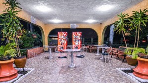 An outdoor patio area with tables and chairs, potted plants, and a vending machine. - Vagabond Inn Costa Mesa (Costa Mesa)