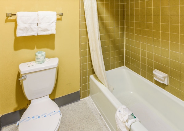 Un baño con inodoro, bañera y cortina de ducha.