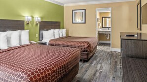 A hotel room with two beds, a desk, and a bathroom visible through an open door. - Vagabond Inn Costa Mesa (Costa Mesa)