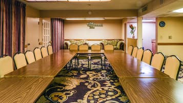 A conference room with a long table, chairs, a patterned carpet, and a clock on the wall.