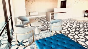 Un hall d’entrée doté d’un sol à motifs géométriques, d’un comptoir de réception et d’espaces d’attente avec des tables rondes et des fauteuils confortables.
