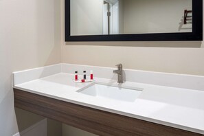 A bathroom with a white sink, a mirror, and a wooden vanity.