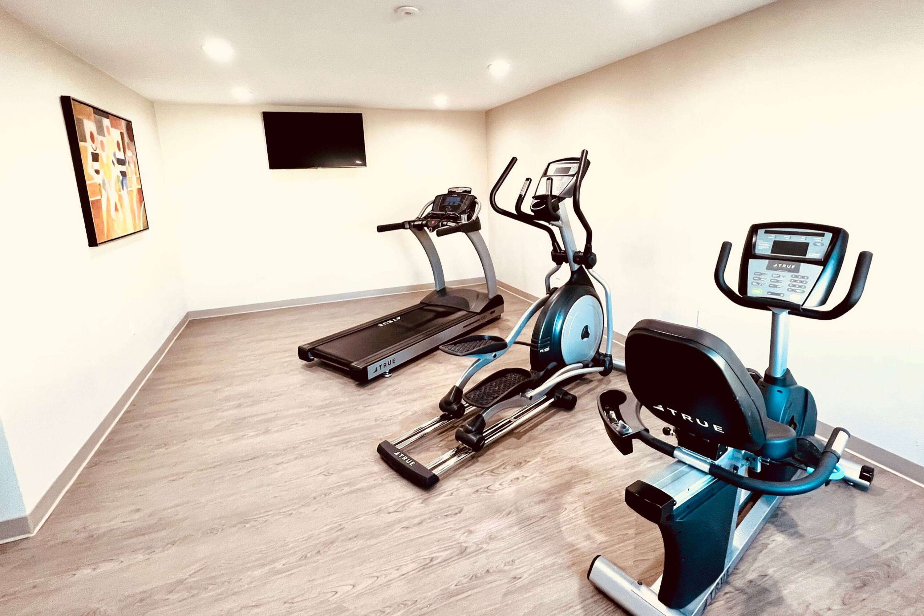 Ein Heimfitnessraum mit Laufband, Crosstrainer und Ergometer.