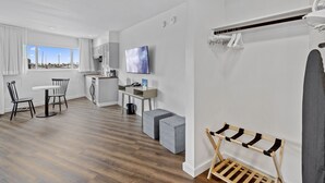 A modern, well-lit room with a dining area, kitchenette, and a large window offering a city view. - Sea Harbor Hotel (San Diego)