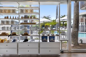 A well-lit retail area with shelves displaying various products, a poolside view, and a palm tree. - Sea Harbor Hotel (San Diego)