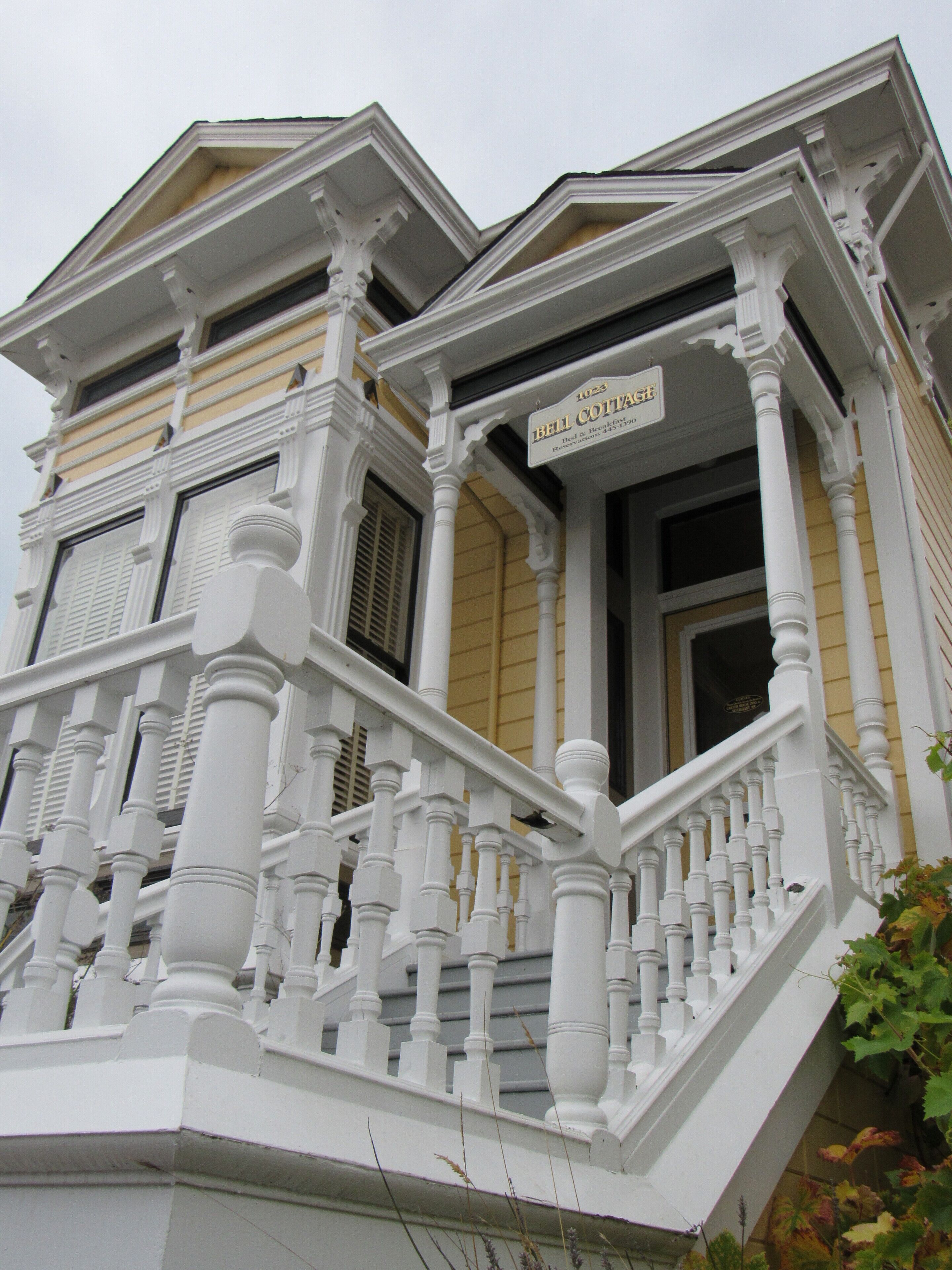 A two-story house with a balcony and a sign that reads "Bell Cottage."