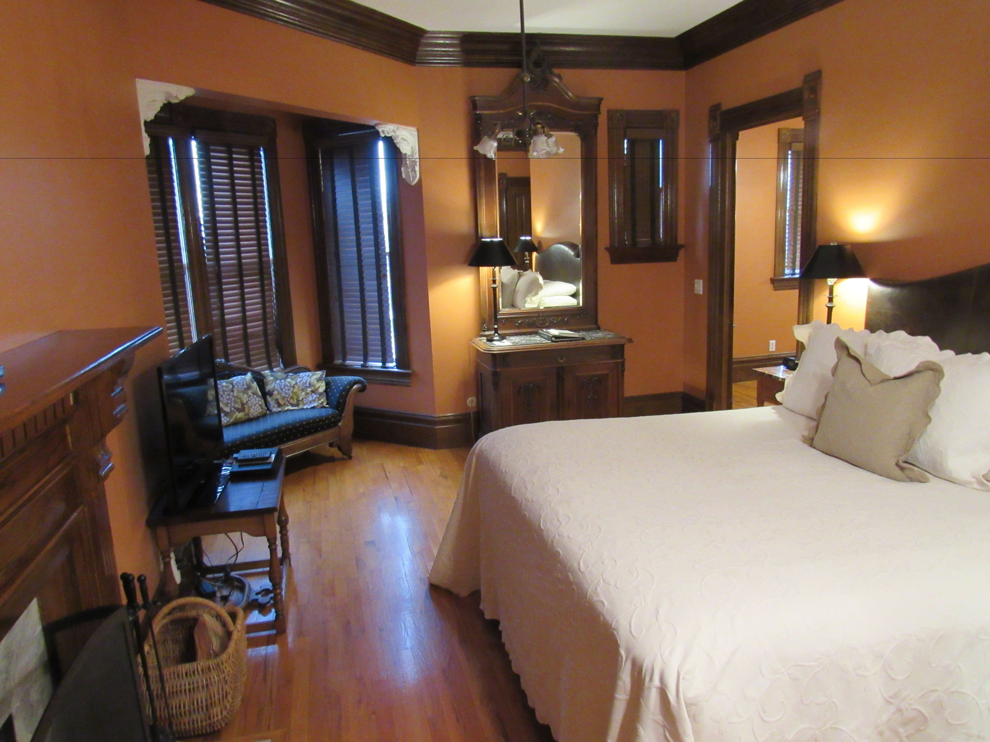 Habitación de hotel con una cama grande, zona de estar con sofá, cómoda y espejo.