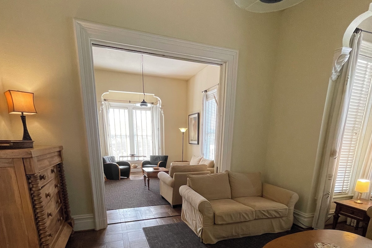 A living room with a wooden floor, a beige sofa, a round coffee table, and a wooden cabinet.