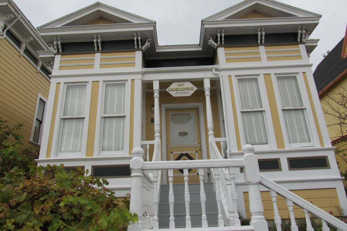 A Victorian-style house with a prominent front porch, a sign reading "Carter Cottage," and a staircase leading to the entrance.