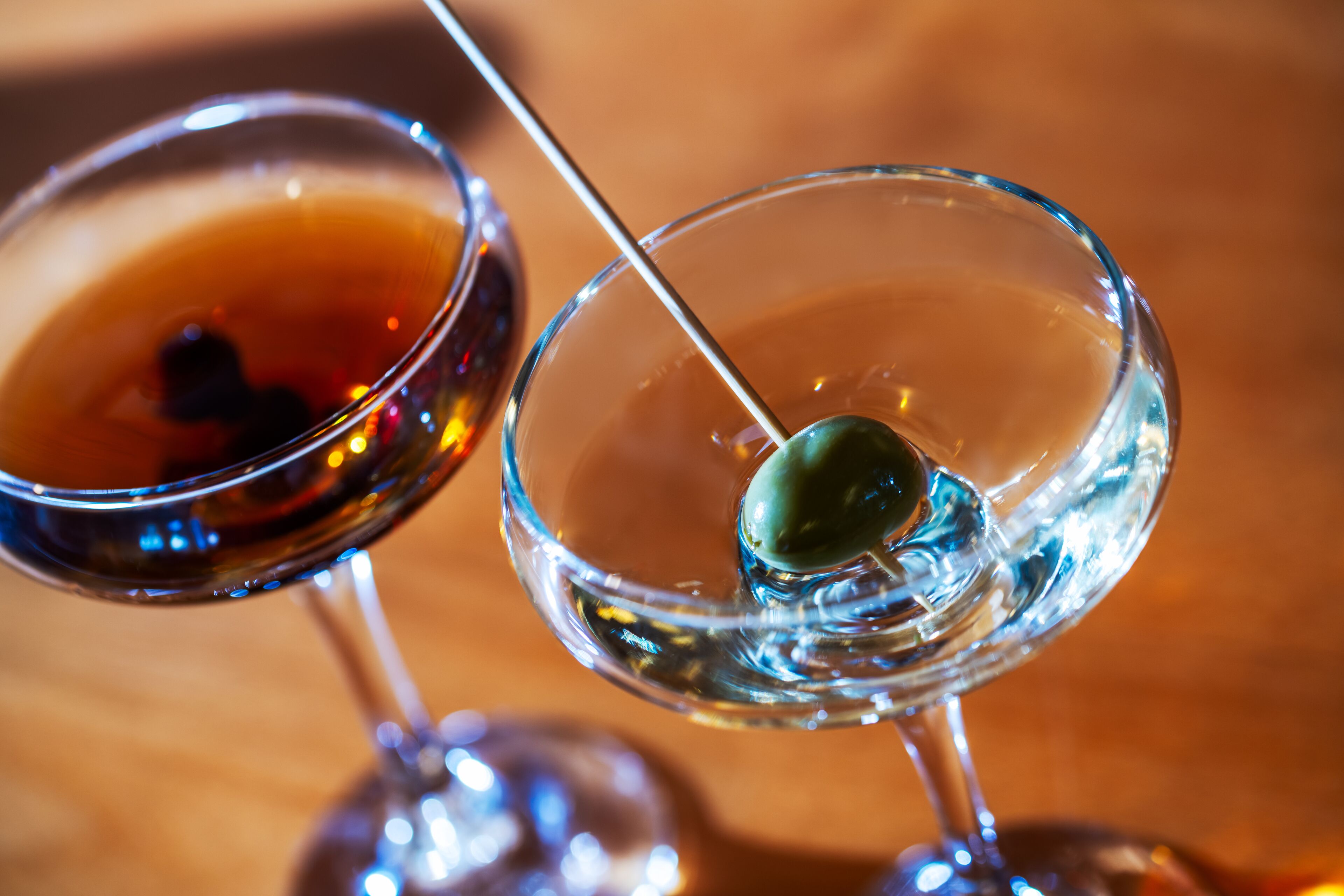 Dos copas de martini con aceitunas verdes ensartadas.