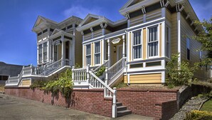 A row of Victorian-style houses with a central staircase, brick foundation, and a clear blue sky. - Carter House Inns (Eureka)