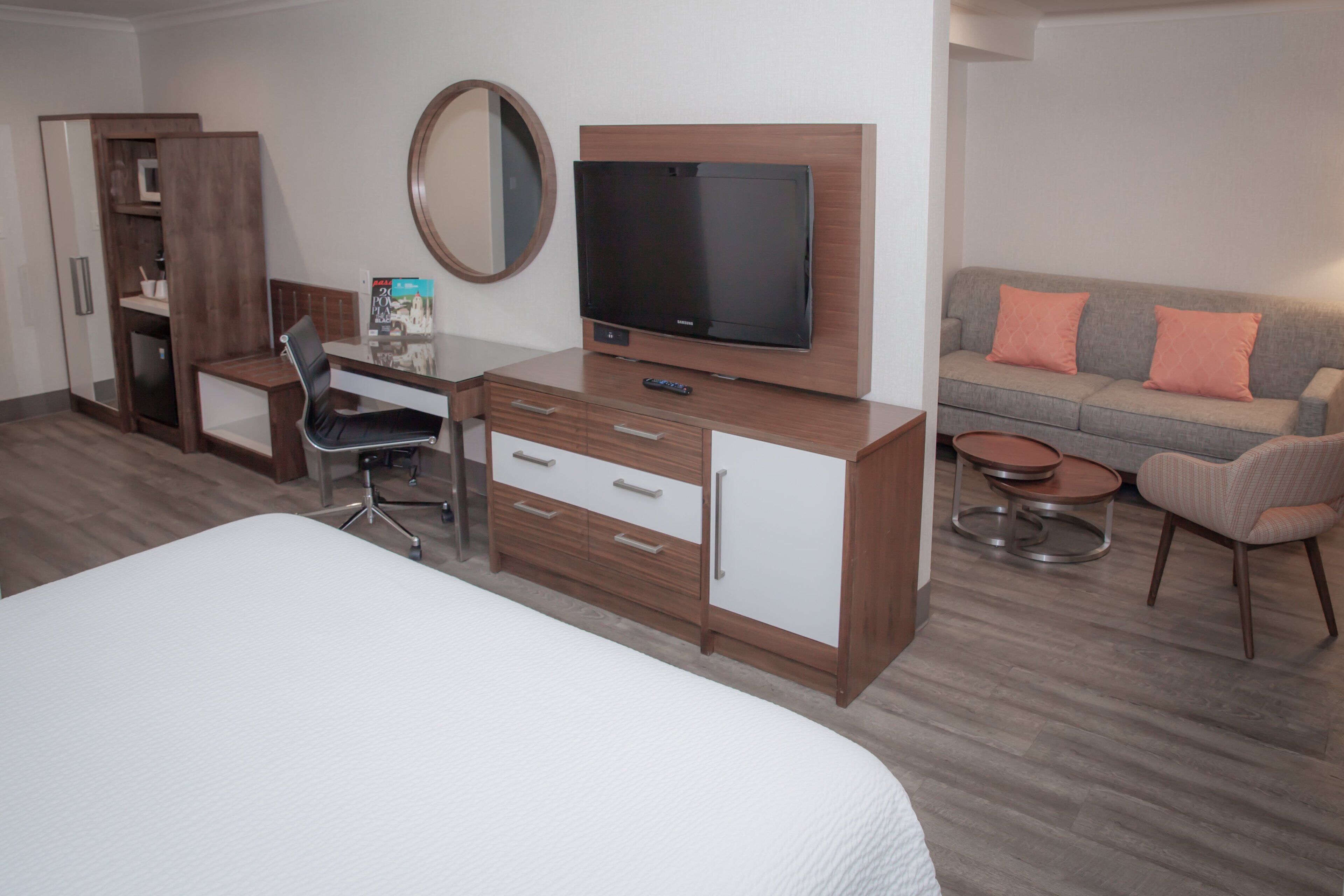 Habitación de hotel con cama, escritorio y silla, televisor, sofá y una mesita.