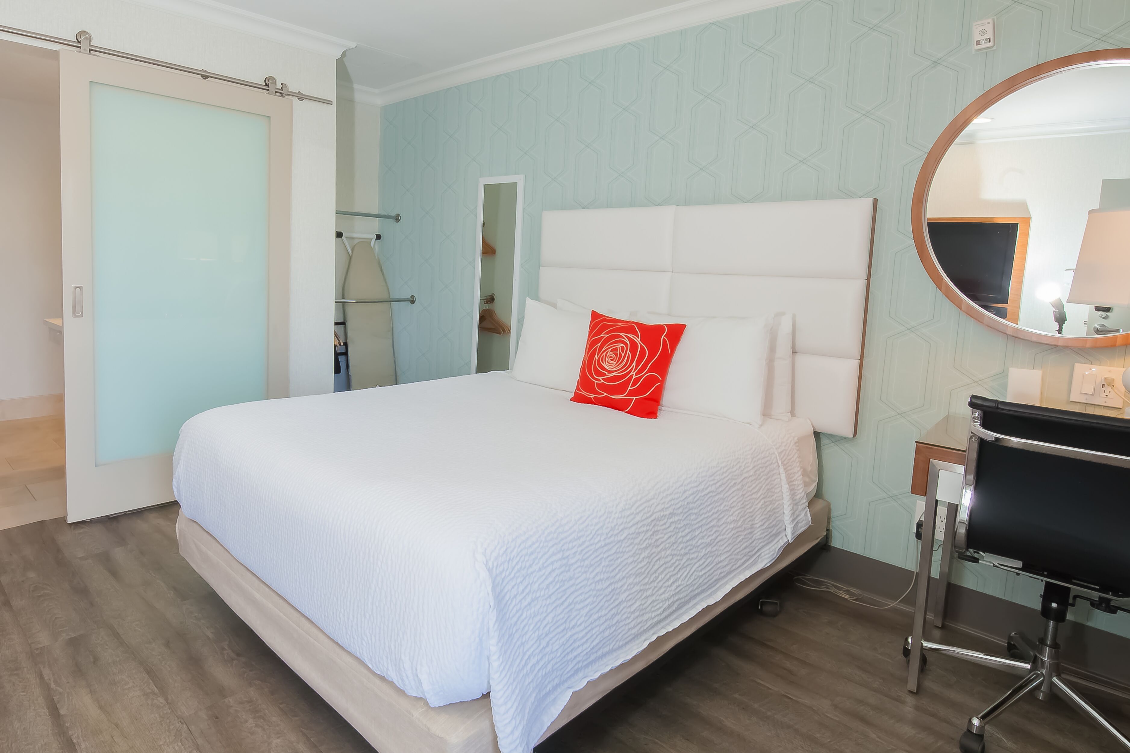 Een hotelkamer met een bed, een bureau, een spiegel en een kledingkast.
