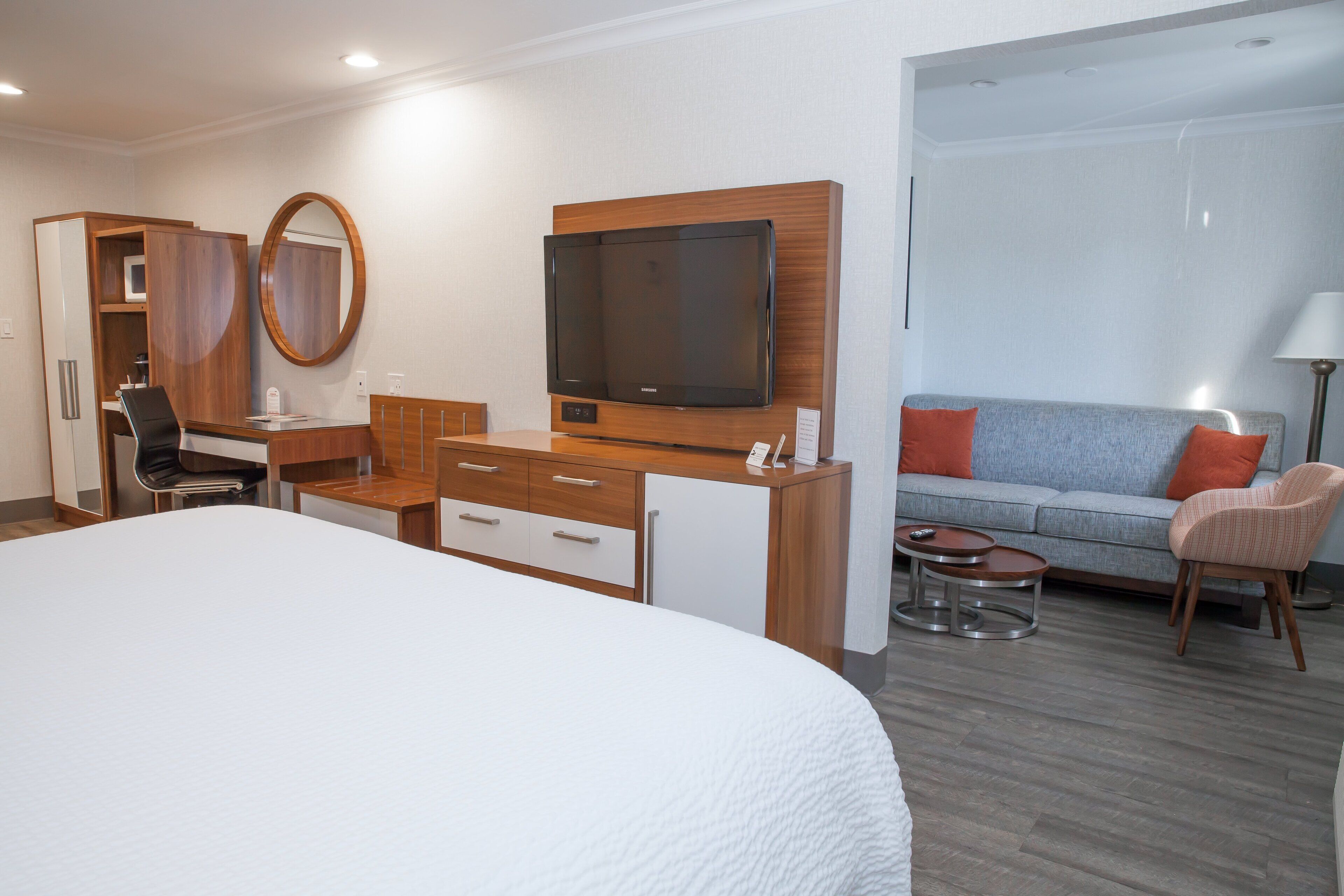 Habitació d'hotel amb un llit gran, una taula de treball amb una cadira, una televisió, un sofà i una taula petita.