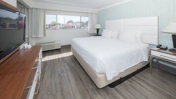 Habitación de hotel con una cama grande, un televisor de pantalla plana, un escritorio con silla y una ventana con cortinas.