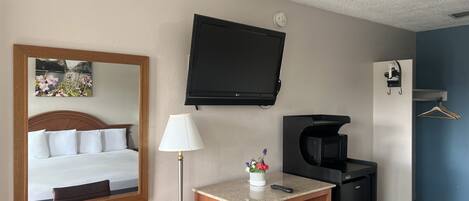 Une chambre d’hôtel équipée d’un lit, d’un bureau avec une lampe, d’une télévision, d’un four à micro-ondes et d’un réfrigérateur.